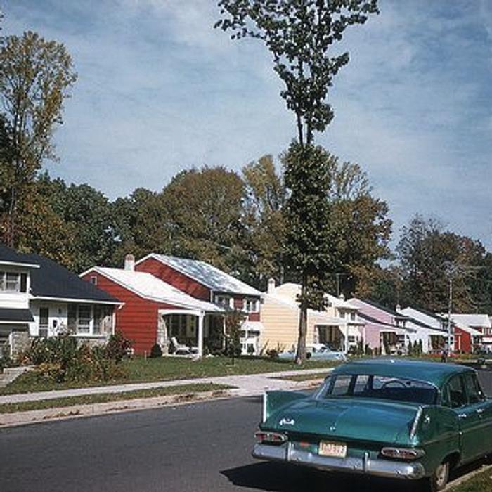 A street of 1960s cars and houses
